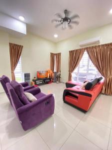 sala de estar con 2 sofás morados y TV en Patience Homestay Kuala Selangor en Kuala Selangor
