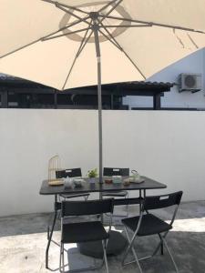 a table with an umbrella and two chairs at Patience Homestay Kuala Selangor in Kuala Selangor
