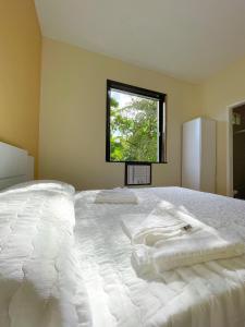 a bedroom with a large white bed with a window at Hotel Boavista in Miguel Pereira