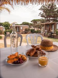 a table with two plates of bread and a bottle of orange juice at Camping Le Calypso 5 étoiles in Torreilles
