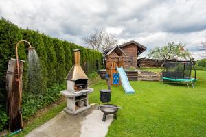a backyard with a stone grill and a playground at Drevenica Emilka - Sprcha, Záhradná hojdačka, Ohnisko in Brezno