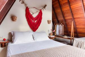 a bedroom with a bed with a red feather on the wall at Aldeia dos Corais - Taipu de Fora in Barra Grande