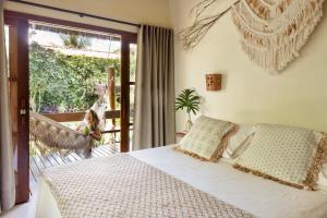 a bedroom with a bed and a child sitting on a porch at Aldeia dos Corais - Taipu de Fora in Barra Grande