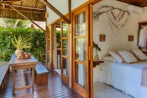 a bedroom with a bed and a table and glass doors at Aldeia dos Corais - Taipu de Fora in Barra Grande