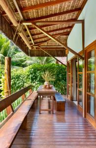 a wooden deck with a table and benches at Aldeia dos Corais - Taipu de Fora in Barra Grande