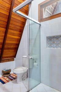a bathroom with a toilet and a glass shower at Aldeia dos Corais - Taipu de Fora in Barra Grande