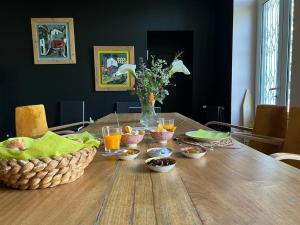 una mesa de madera con tazones de comida encima en Suite campagnarde près Bordeaux, vue sur les vignes au Château Camponac, en Bourg-sur-Gironde