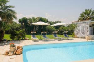 a pool with chairs and umbrellas in a yard at B&B Tenuta Martinelli in Monopoli