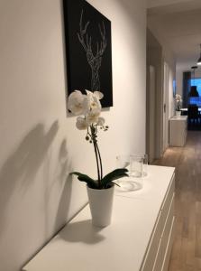 a white vase with white flowers on a white table at Modern Spacious 3 Bedroom Apartment With Balcony At Richard Mortensens Vej Close To The Royal Arena And Fields in Copenhagen