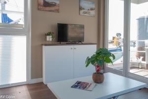 a living room with a tv and a white table at AV Amsterdam Casa Flotante in Gijón