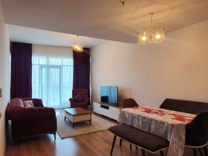 ein Wohnzimmer mit einem Sofa, einem Tisch und einem TV in der Unterkunft MALL OF ISTANBUL RESIDENCE in Mahmutbey