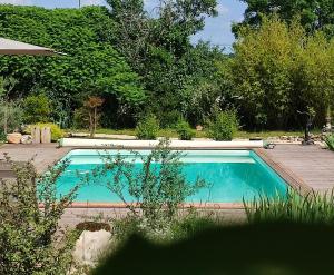 einen Pool in einem Garten mit Bäumen in der Unterkunft A deux pas de St Cirq Lapopie, La chambre du "cocher" des Murets de L'isa in Esclauzels