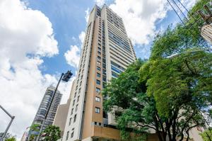 un edificio alto con un árbol delante de él en Studio incrível no condomínio clube sky Batel soho, en Curitiba