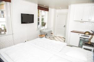 a white bedroom with a bed and a tv on the wall at Johannas GuestHouse in Söderköping