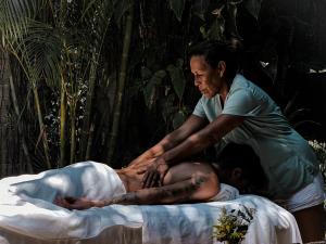 a man getting a massage from a woman on a bed at La Punta surfhouse in Puerto Escondido