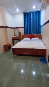 a bedroom with a bed with a blue curtain at Hoàng Anh Hotel in Ho Chi Minh City