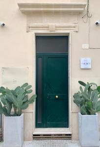 HABITARE Lecce & Salento في ليتشي: باب أخضر على مبنى به مزرعتين الفخار