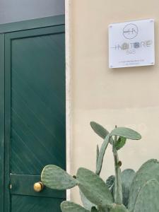una planta junto a una puerta con un cartel en la pared en HABITARE Lecce & Salento, en Lecce