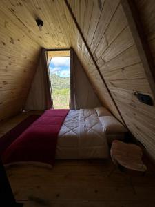 um quarto com uma cama numa tenda com uma janela em Chalés entre Nuvens em Campos do Jordão