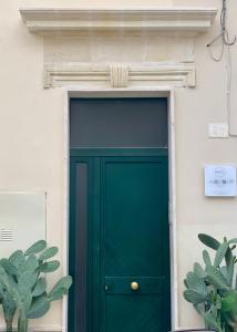 HABITARE Lecce & Salento في ليتشي: باب أخضر على بناية بيضاء فيها نباتات