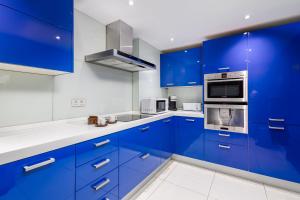 una cocina azul con paredes blancas y armarios azules en Puerto Banús, Edificio Tembo, 2 bedroom apartment, parking and pool, en Marbella