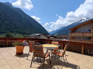una mesa y sillas en un balcón con montañas en Pension Alpina Neustift en Neustift im Stubaital