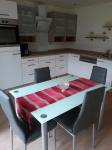 una cocina con una mesa blanca con sillas y una manta roja en Haus Wassermann, en Kleblach