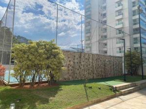 una valla frente a un edificio con árboles en Apartamento com Excelente Vista!, en Santos