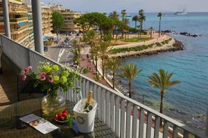 einen Tisch mit einer Flasche Wein und Blumen auf dem Balkon in der Unterkunft Royal Antibes - Luxury Hotel, Résidence, Beach & Spa in Antibes