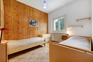 2 Betten in einem Zimmer mit Holzwänden in der Unterkunft Casa Nova in Dare