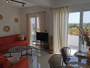 Luxury Apartment Olea Afandou في أفانتو: غرفة معيشة مع أريكة حمراء وتلفزيون
