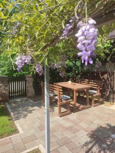 a picnic table and bench under a tree with purple flowers at Guest House Josipović in Korenica