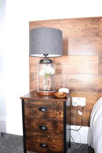 una lámpara en un tocador de madera junto a una cama en Woodlyn Guest House, en Gatehouse of Fleet
