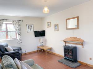 a living room with a fireplace and a tv at Sweetbriar Holiday Cottage by Trident Holiday Homes in Kilmore Quay