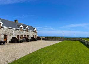 a large stone building with a grass field next to it at Sweetbriar Holiday Cottage by Trident Holiday Homes in Kilmore Quay