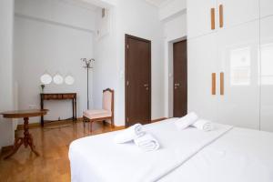 Cette chambre blanche comprend deux lits et une table. dans l'établissement Junita's house, à Athènes