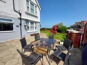 a patio with a glass table and chairs at Westbrook Lodge Guest House in Margate