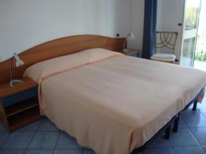 1 dormitorio con 1 cama grande con colcha blanca en Hotel Casa Gerardo, en Isquia