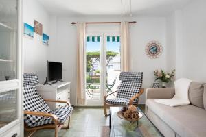 a living room with a couch and chairs and a tv at Barrosa Primera línea de playa in Chiclana de la Frontera