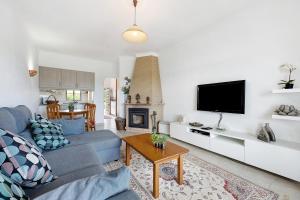uma sala de estar com um sofá azul e uma televisão em Mar e Campo em Barão de São João