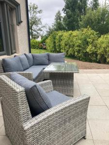 a wicker couch and a table on a patio at Chic Classy & Cosy in Lough Erne 5* Resort in Ballycassidy