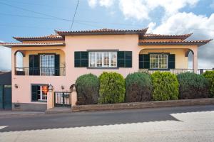 a pink house with black windows and a fence at Apartamento Maria in Canhas