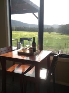 a table with a bottle of wine and a window at Blaze Rock Retreat in Halls Gap