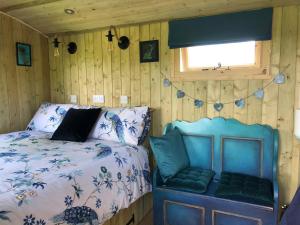 a bedroom with a bed and a window at The Peacock Shepherds Hut at Hafoty Boeth in Corwen