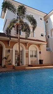 a house with a palm tree in front of a swimming pool at Aleena's Guesthouse BSD City in Tangerang