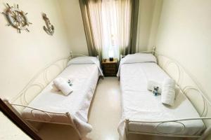2 camas en una habitación con sábanas blancas y toallas en Apartamento Camaleón, en Chipiona