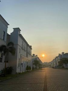 a street with buildings and a sunset in the background at Aleena's Guesthouse BSD City in Tangerang
