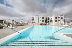 a swimming pool with stairs next to some buildings at Casa Mae in Caleta De Fuste