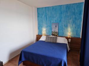 a bedroom with a blue bed and a painting of a lighthouse at Apartamentos Wundermar in Torredembarra
