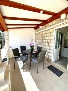 patio con mesa, sillas y pared de ladrillo en Villa Mare & Filip 2 en Zaton